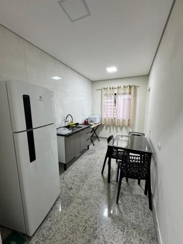 a kitchen with a refrigerator and a table in it at Casa nova e confortavel, Itabirito, MG in Itabirito