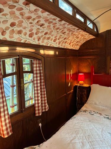 a bedroom with a bed and windows on a boat at Idyllic Roulotte in Les Assions
