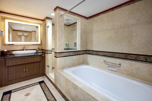 a bathroom with a large tub and a sink at Novotel Solo in Solo
