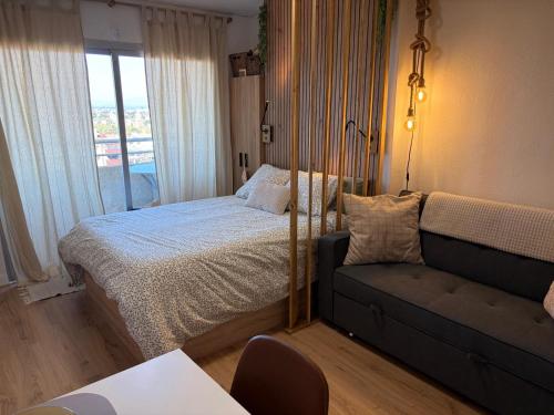 a bedroom with a bed and a couch and a window at Tamy-Home in Empuriabrava