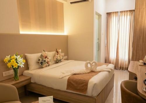 a bedroom with a bed with a vase of flowers on it at Downtown Business Hotel in Singapperumālkovil