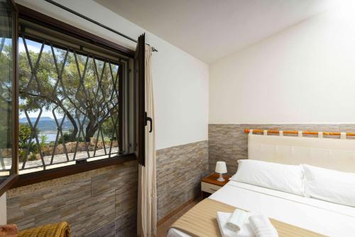 a bedroom with a bed and a window at Panoramic Seaview Coastal Retreat with Pool in Cugnana