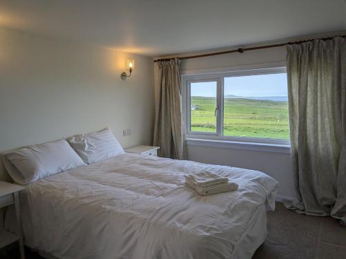 a bedroom with a white bed with a window at Rousay&nbspCottage in Orkney