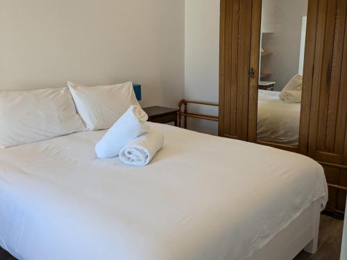 a white bed with two pillows and a mirror at Lower Cottage in Orkney