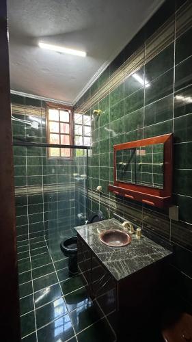 a green tiled bathroom with a sink and a toilet at Casa Aparecida in Aparecida