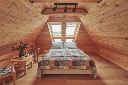 a bedroom with a bed in a wooden cabin at Królowa Kaczek - własna plaża, pomost, sauna z widokiem na wodę i sala warsztatowa in Sorkwity