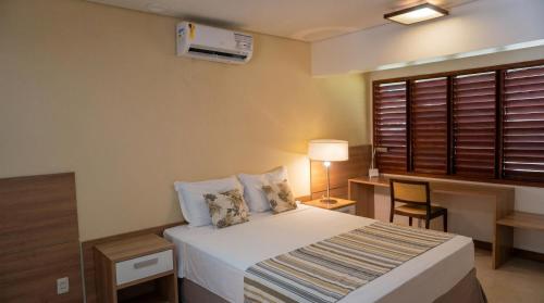 ein Schlafzimmer mit Bett, Schreibtisch und Fenster in der Unterkunft Domus Hotel - Núcleo Urbano de Carajás in Parauapebas