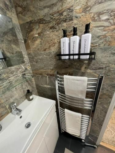 a bathroom with a sink and a chair with three bottles at The Wigmore house in Luton