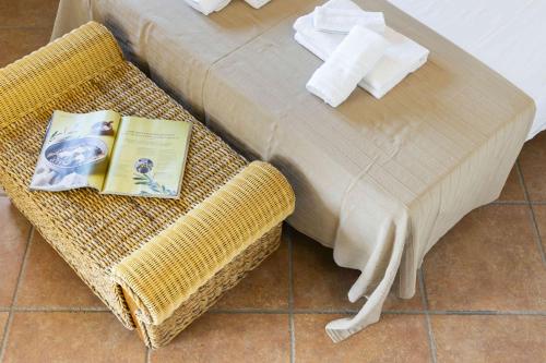 a wicker bench with a book on it next to a bed at Panoramic Seaview Coastal Retreat with Pool in Cugnana