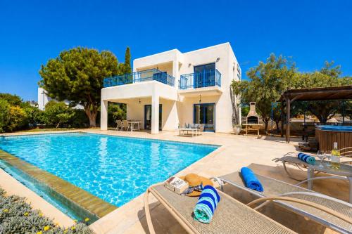 a villa with a swimming pool in front of a house at Villa Estia in Peyia