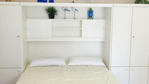 a bed in a white bedroom with white shelves at Stettiner Str 6b in Grömitz