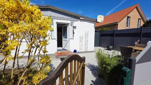 a white house with a wooden gate and a fence at Stettiner Str 6b in Grömitz