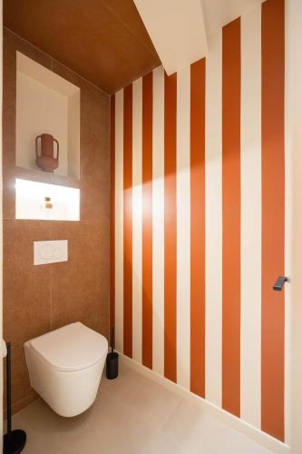 ein Badezimmer mit Toilette und orange-weißen Streifen in der Unterkunft minuit - Love Room avec jacuzzi privatif et hammam Marseille Aix in Vitrolles
