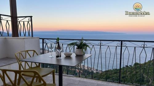a table with a bottle of wine and chairs on a balcony at Domus Mea, Case Vacanza Vista Mare vicino Taormina in Forza dʼAgro