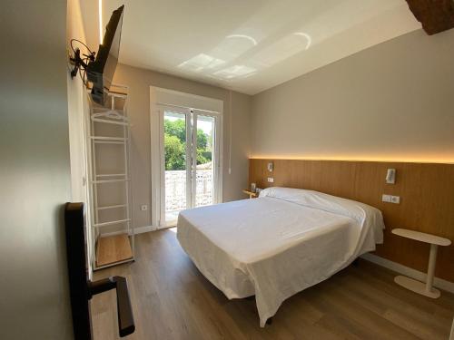 a bedroom with a white bed and a window at PENSIÓN SANTA CLARA in Pontevedra