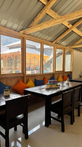 a dining room with a table and chairs and windows at SAANJH, Shangarh in Shangarh