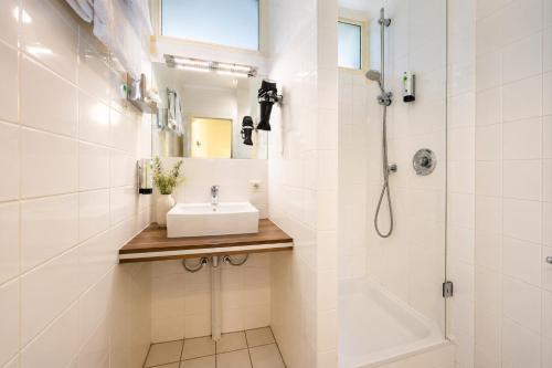 a white bathroom with a sink and a shower at Turmhotel Rhein-Main - klimatisierte Apartments in Dreieich