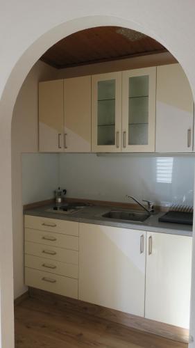 a kitchen with white cabinets and an archway at Tildes Apartments in Reifnitz