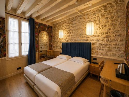 a bedroom with a large bed and a desk at Hôtel de Notre-Dame in Paris