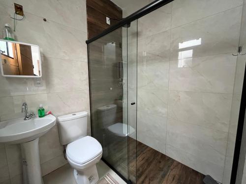 a bathroom with a toilet and a glass shower at Casa moderna em Itapoá SC in Itapoa