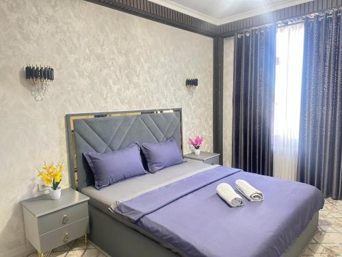 a bedroom with a large bed with purple sheets and pillows at КАРАВАН САРАЙ 15 Венеция in Türkistan