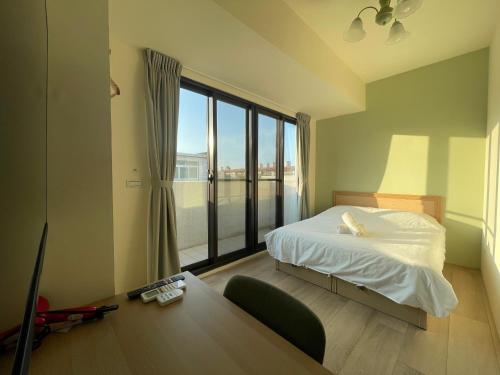 a bedroom with a bed and a desk and a window at 哈樓民宿二館 in Lukang