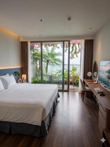 a bedroom with a bed and a desk and a television at Flamingo Cát Bà Sea Residence , Sky Villa Premier Ocean View King Bed in Hai Phong