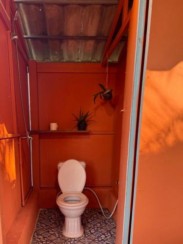 a small bathroom with a toilet in an orange wall at Sea PoeTree in Koh Rong Sanloem