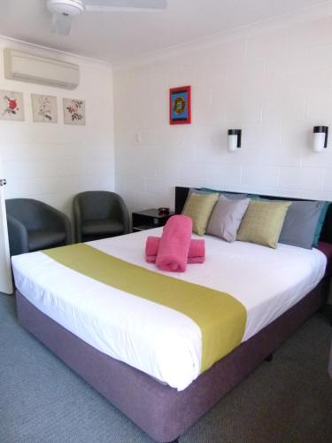 a bedroom with a large bed with pink and yellow sheets at Azalea Motel in Coonabarabran
