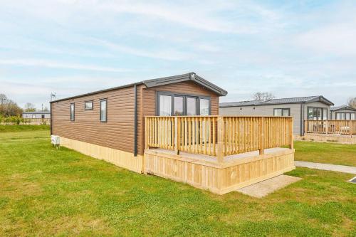 a tiny house with a wooden deck in a yard at Host & Stay - Stag Lodge in Pickering
