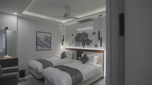 zwei Betten in einem Zimmer mit weißen Wänden in der Unterkunft Alpirious Hotel in Islamabad