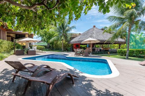 a swimming pool with two chairs and a house at Casa de praia completa in Paulista