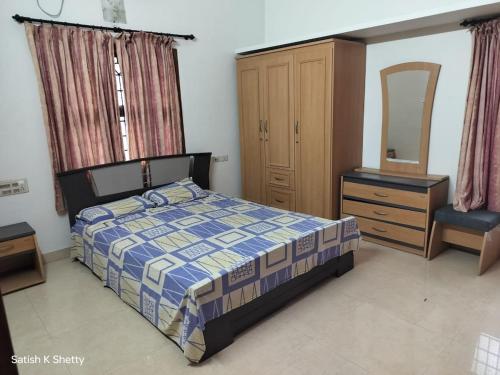 a bedroom with a bed and a dresser and a mirror at Rajmata Nivas in Kaup