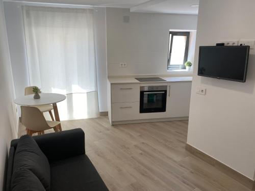 a living room with a couch and a table and a kitchen at Apartamento centro Cubelles in Cubelles