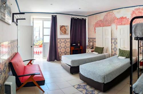 a bedroom with two beds and a red chair at RIA Terrace in Faro
