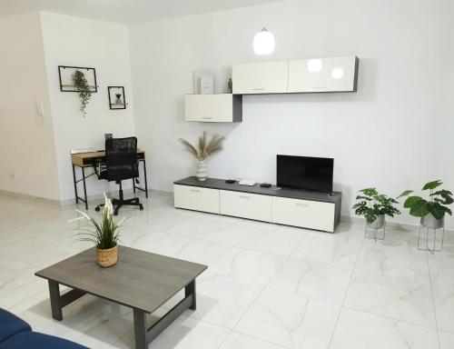 a white living room with a tv and a table at Large and modern apartment in the centre of Malta in Mosta