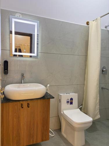 a bathroom with a sink and a toilet and a mirror at Sunset Villa in Mysore