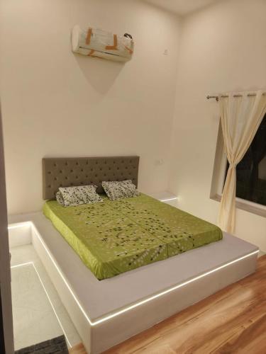 a bedroom with a bed with a green comforter at Sunset Villa in Mysore