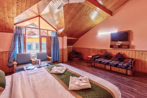 a room with a bed and a couch and a tv at Hotel Naveen Manali in Manāli