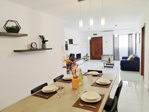 a dining room with a table with plates and wine glasses at Large and modern apartment in the centre of Malta in Mosta