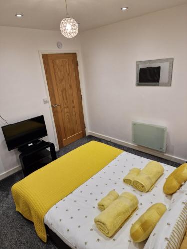 a bedroom with a bed with yellow blankets and a television at Cosynite B&B for 2 in Birmingham