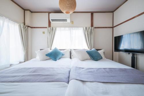 a bedroom with two beds and a tv and window at KEI HOUSE Yamato 101 in Yamato