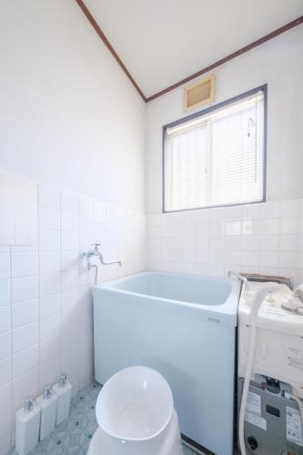 a white bathroom with a tub and a toilet at KEI HOUSE Yamato 101 in Yamato