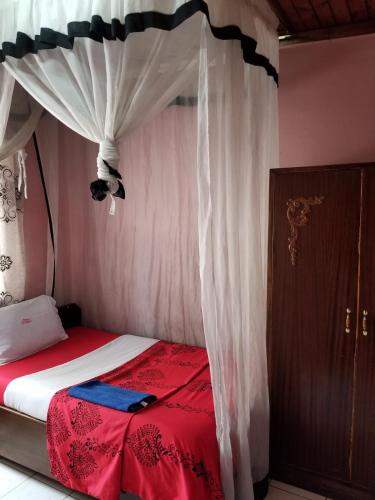 a bedroom with a canopy bed with a red blanket at Chumber Hotel in Gatunga