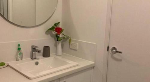 a bathroom with a sink and a vase with a rose at Deluxe Queen Room in Perth
