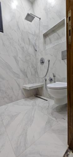 a white bathroom with a shower and a toilet at Maison salakta in Ksour Essaf