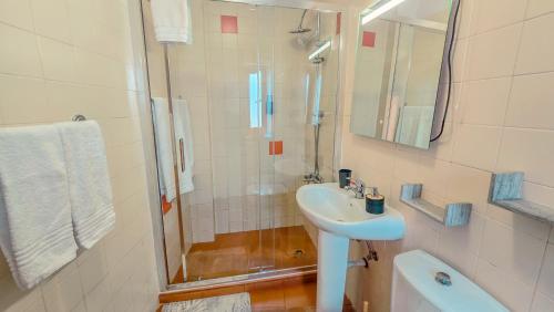 a white bathroom with a sink and a shower at Évora City Break Apartment with Patio in the Historic Centre in Évora