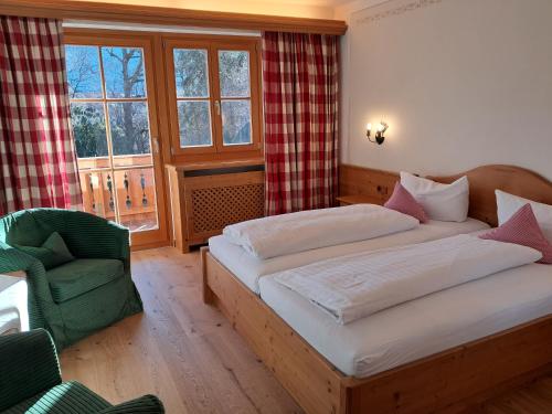 a bedroom with two beds and a chair and a window at Hotel Seerose in Rottach-Egern