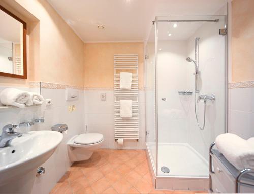a bathroom with a shower and a toilet and a sink at Hotel Seerose in Rottach-Egern