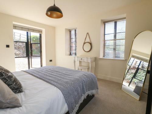 a bedroom with a bed and a mirror and windows at Gardeners Cottage in Oakham